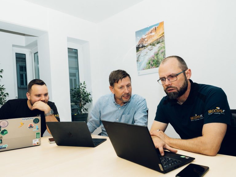Start Das SECOSYS-IT Team bespricht ein Projekt am Laptop im Büro Erfurt