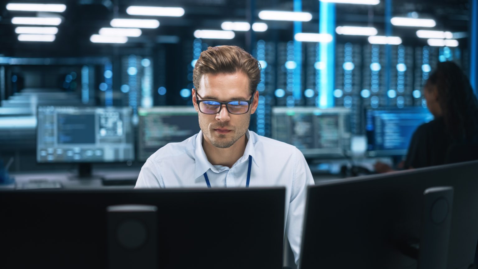 Techniker überwacht IT-Systeme an mehreren Monitoren