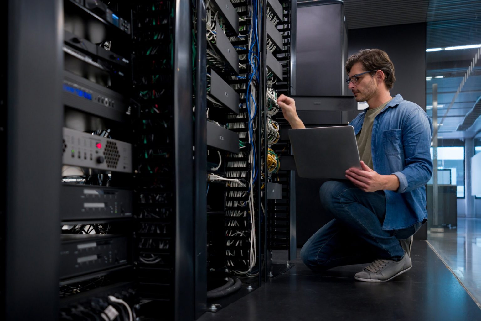 Techniker prüft Netzwerkkomponenten im Serverschrank