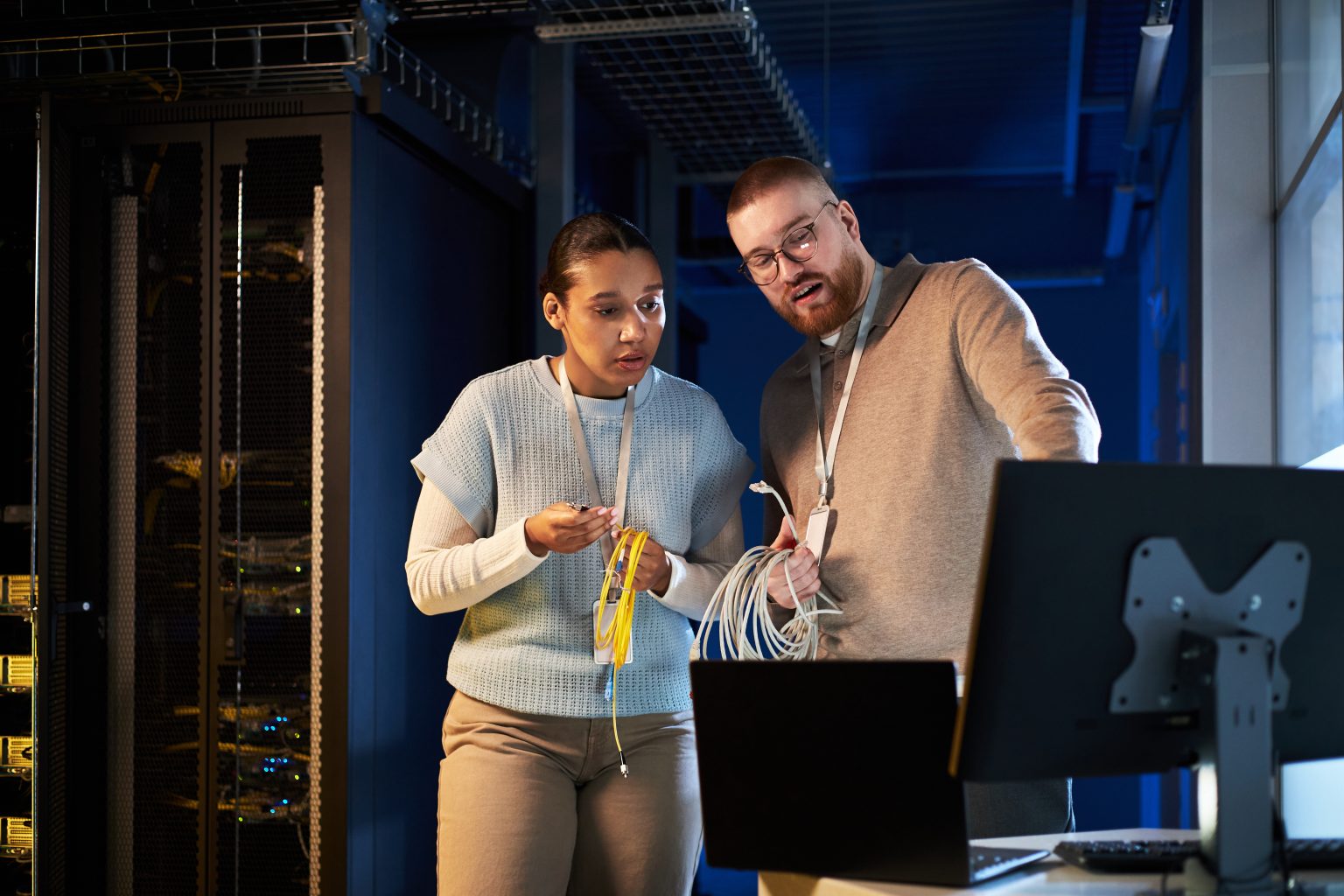 Zwei Techniker mit Netzwerkkabeln im Serverraum
